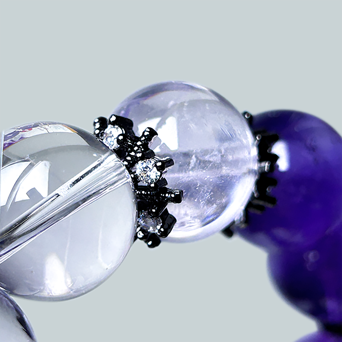 Ultra close-up of clear quartz and light amethyst beads with black snowflake spacers, showcasing sparkle and bead clarity.