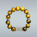 Bracelet with yellow tiger eye beads and silver centerpiece and spacers on a gray background