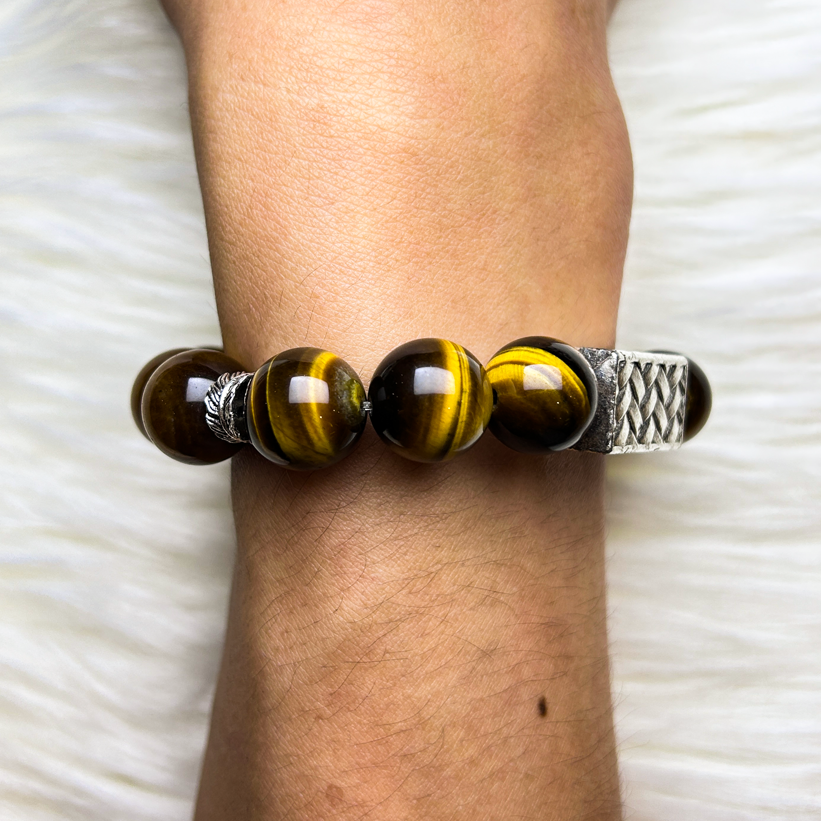 Bracelet with yellow tiger eye beads on a wrist against a white background